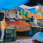 A lively outdoor market scene showcasing vendors selling fresh fruits and vegetables.