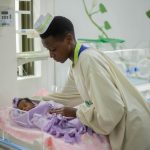 A compassionate nurse tends to a newborn in a hospital nursery, symbolizing care and dedication.