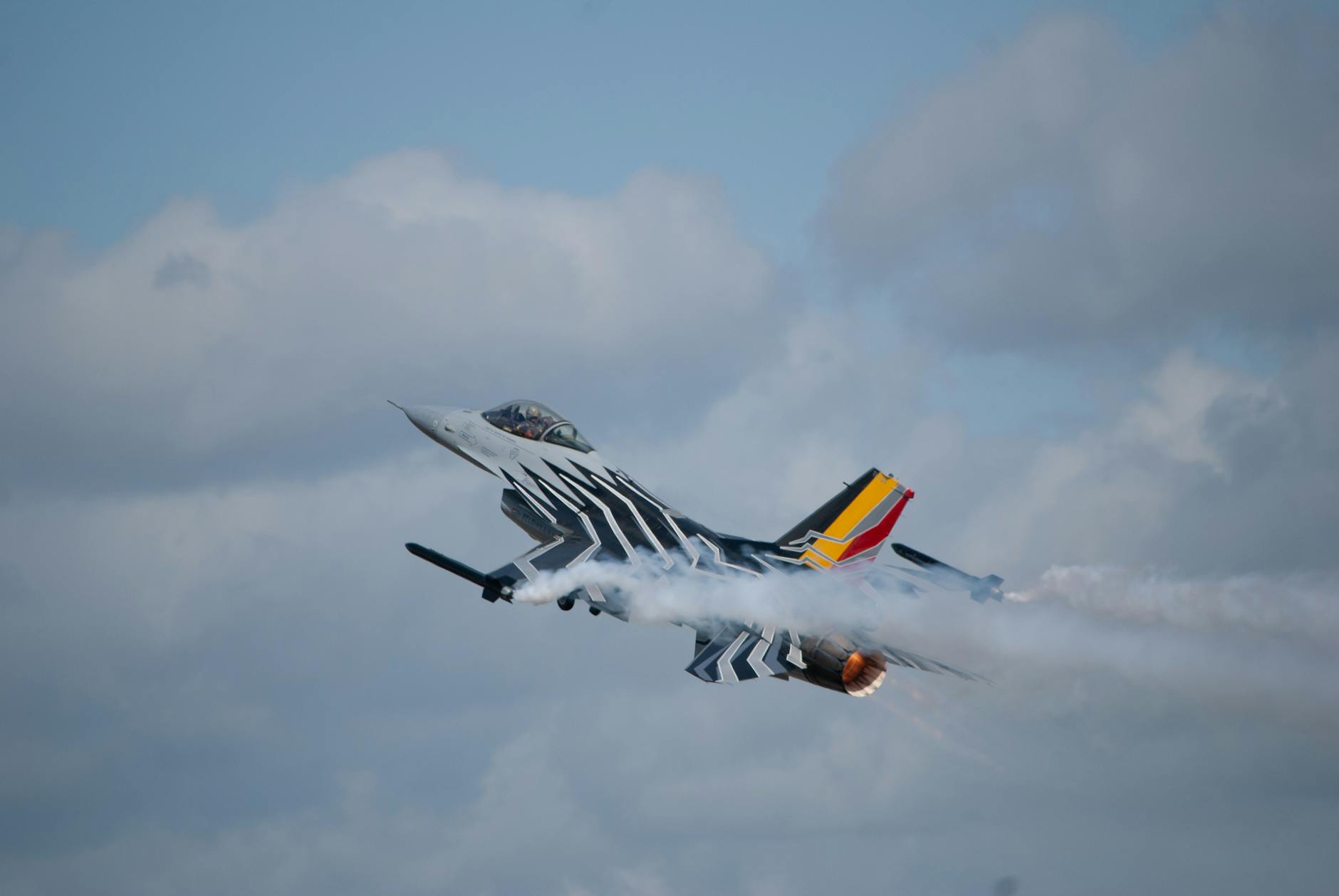 A dramatic airshow performance featuring a military jet with smoketrails in Fairford, UK.