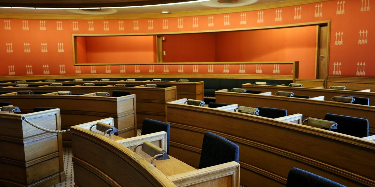 An empty parliamentary meeting room with wooden seating and vibrant orange walls in Oslo, Norway.