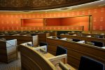 An empty parliamentary meeting room with wooden seating and vibrant orange walls in Oslo, Norway.