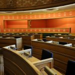 An empty parliamentary meeting room with wooden seating and vibrant orange walls in Oslo, Norway.